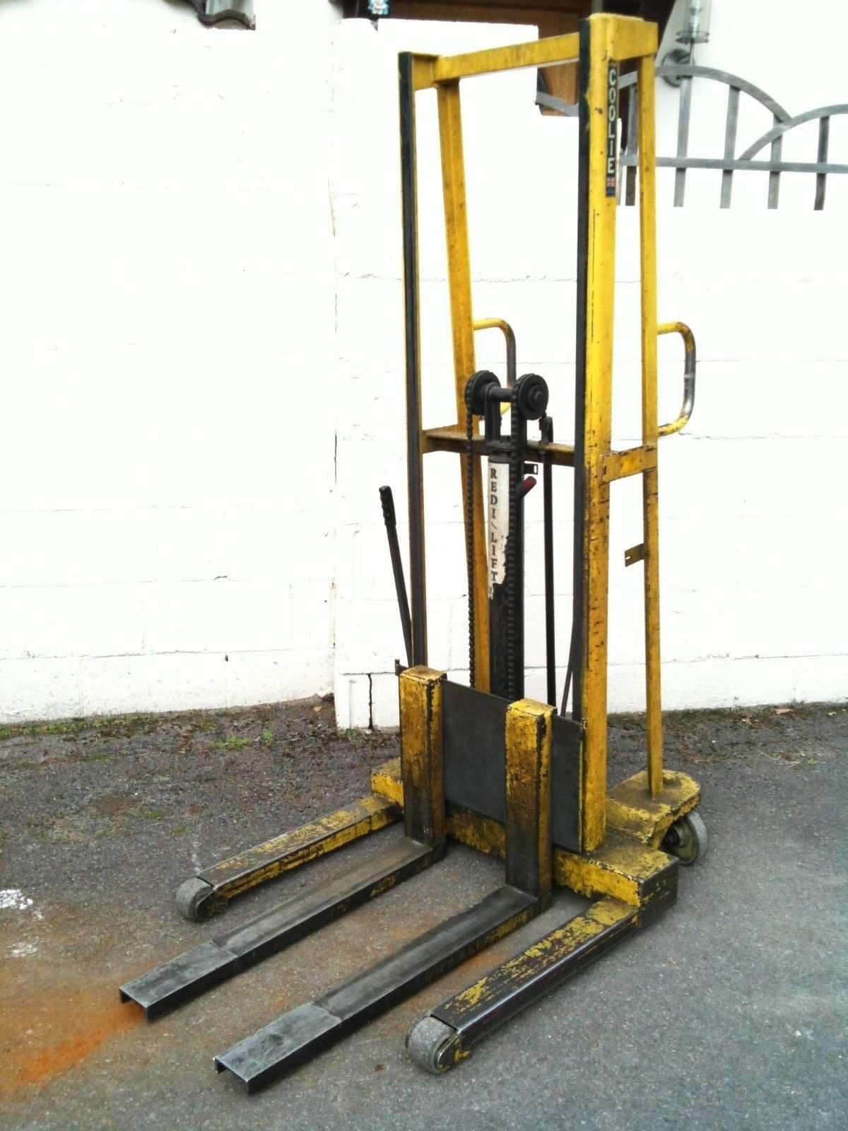 Stacker fork lift lifting pallets in warehouse with operator